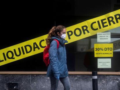 Un mujer pasa frente a un escaparate de una tienda en liquidación en Córdoba, este lunes.