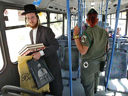 Un judío ultraortodoxo y una policía israelí viajan a bordo de un autobús casi vacío en Jerusalén.