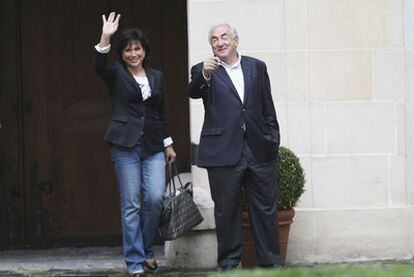 Strauss-Kahn y su esposa, Anne Sinclair, saludan desde la entrada de su apartamento en la plaza de los Vosgos en París.