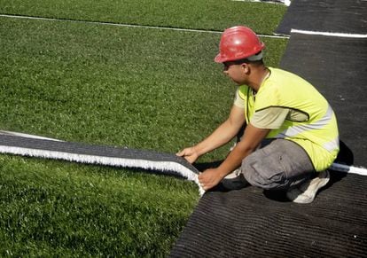 Un operario instala c&eacute;sped artificial en un campo de Barcelona.