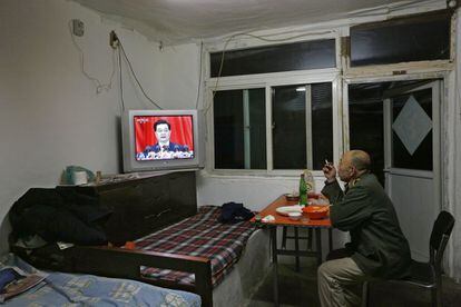 Un hombre cena en su casa de Pekín mientras retransmiten el mensaje de apertura del presidente.