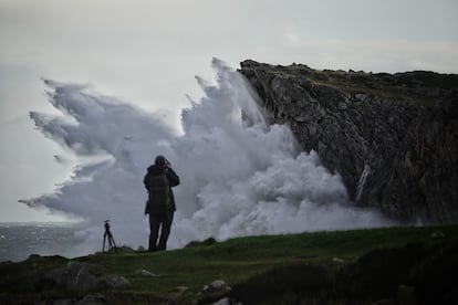 Una persona tomó fotografías del oleaje en los bufones de Pría, este jueves en Llanes, Asturias.