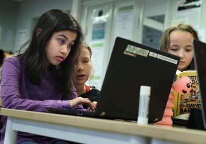 Tres niñas de cuarto curso, de entre 9 y 10 años, preparan sus trabajos en ordenadores.
