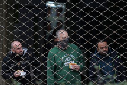 Tres personas miran detrás de las rejas de una sala de juegos durante los enfrentamientos de los manifestantes contra la policía antidisturbios.