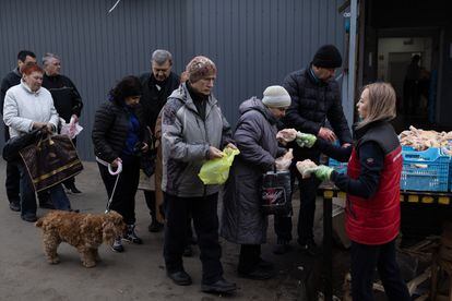 Decenas de vecinos hacen cola para recibir raciones de pollo que reparten voluntarios en el distrito de Kominternovsky, en Járkov. 
