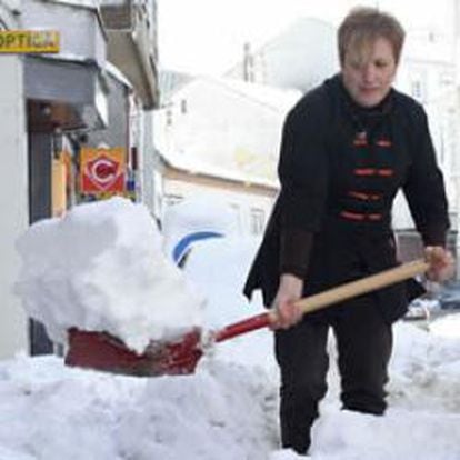 Una mujer retira con una pala la nieve acumulada en el acceso a su vivienda en la localidad lucense de A Fonsagrada.