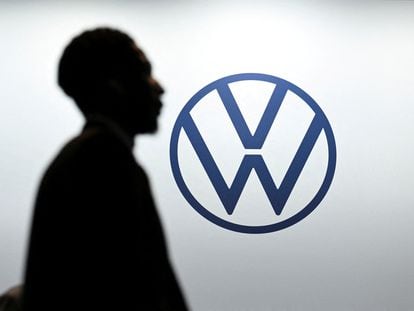 Un hombre pasa enfrente del logo de Volkswagen.