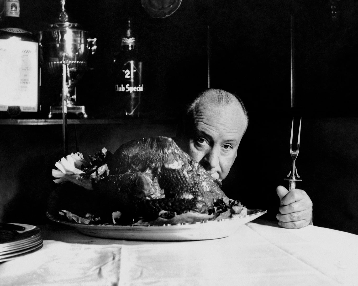 El director Alfred Hitchcock se esconde detrás de un pavo durante una de sus estancias en el Club 21. 
