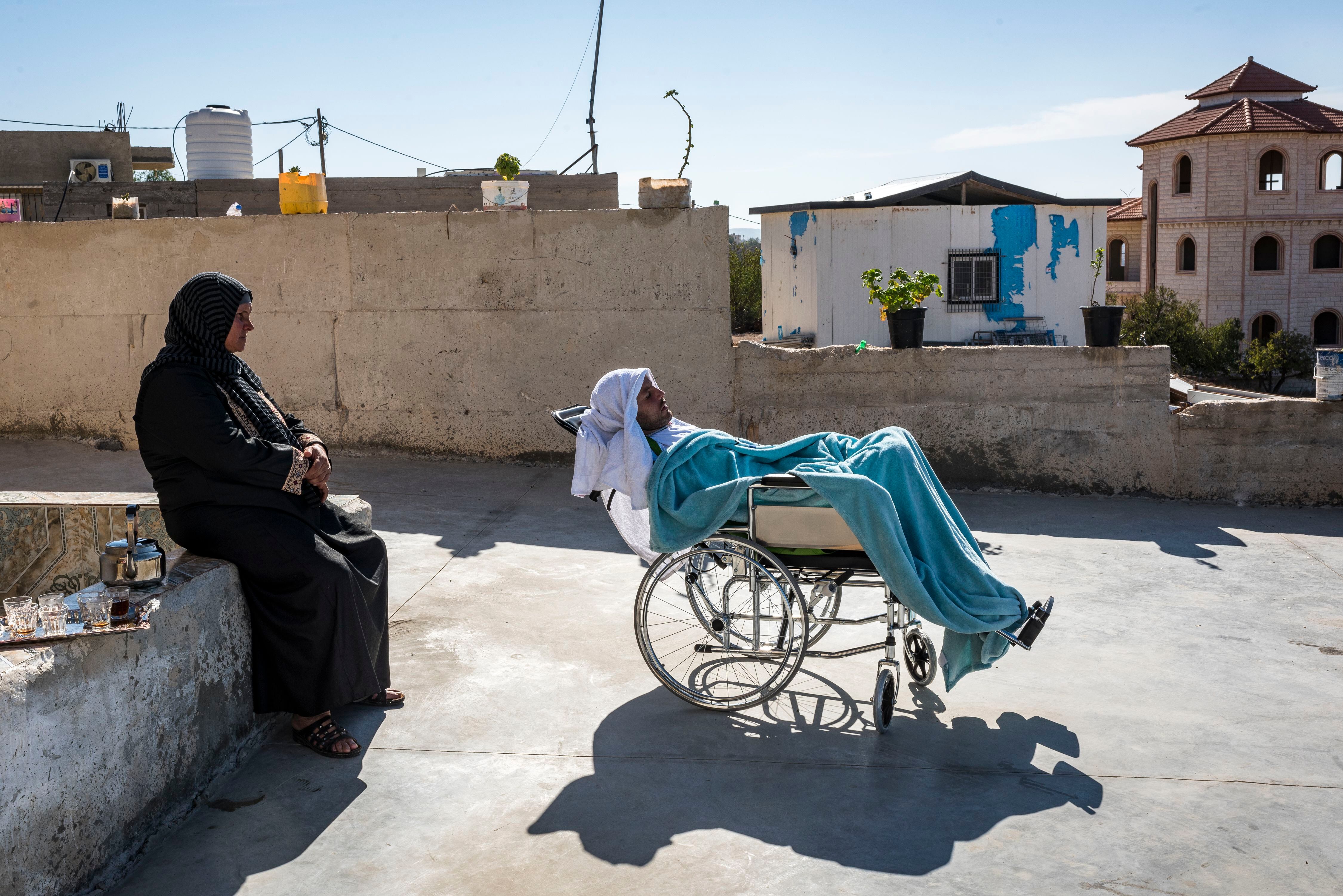 En silla de ruedas, Haroon Abu Aram, de 30 años, que se quedó paralítico por un disparo de un soldado israelí. A su lado, su madre, Faresah.