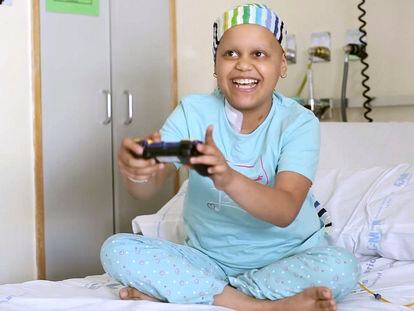 Una niña con cáncer juega a un videojuego en su habitación del hospital.