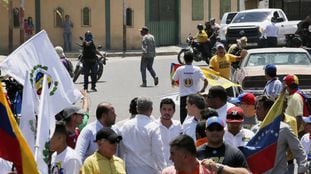 Un hombre con el rostro cubierto apunta a Juan Guaidó con una pistola durante una concentración en Barquisimeto.