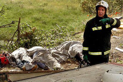 Un bombero trabaja en el lugar del accidente junto a varios de los cadáveres.