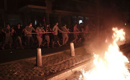 Los manifestantes antifascistas marchan ante un cubo de basura en llamas producto de los enfrentamientos con la policía.