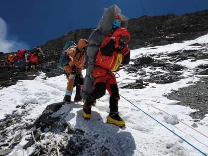 Un sherpa walks transporta a un escalador malasio para rescatarlo en el Monte Everest.