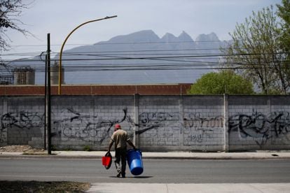Un hombre carga una cubeta y un bote de basura para almacenar agua y transportarla, en la ciudad norteña de Monterrey. 