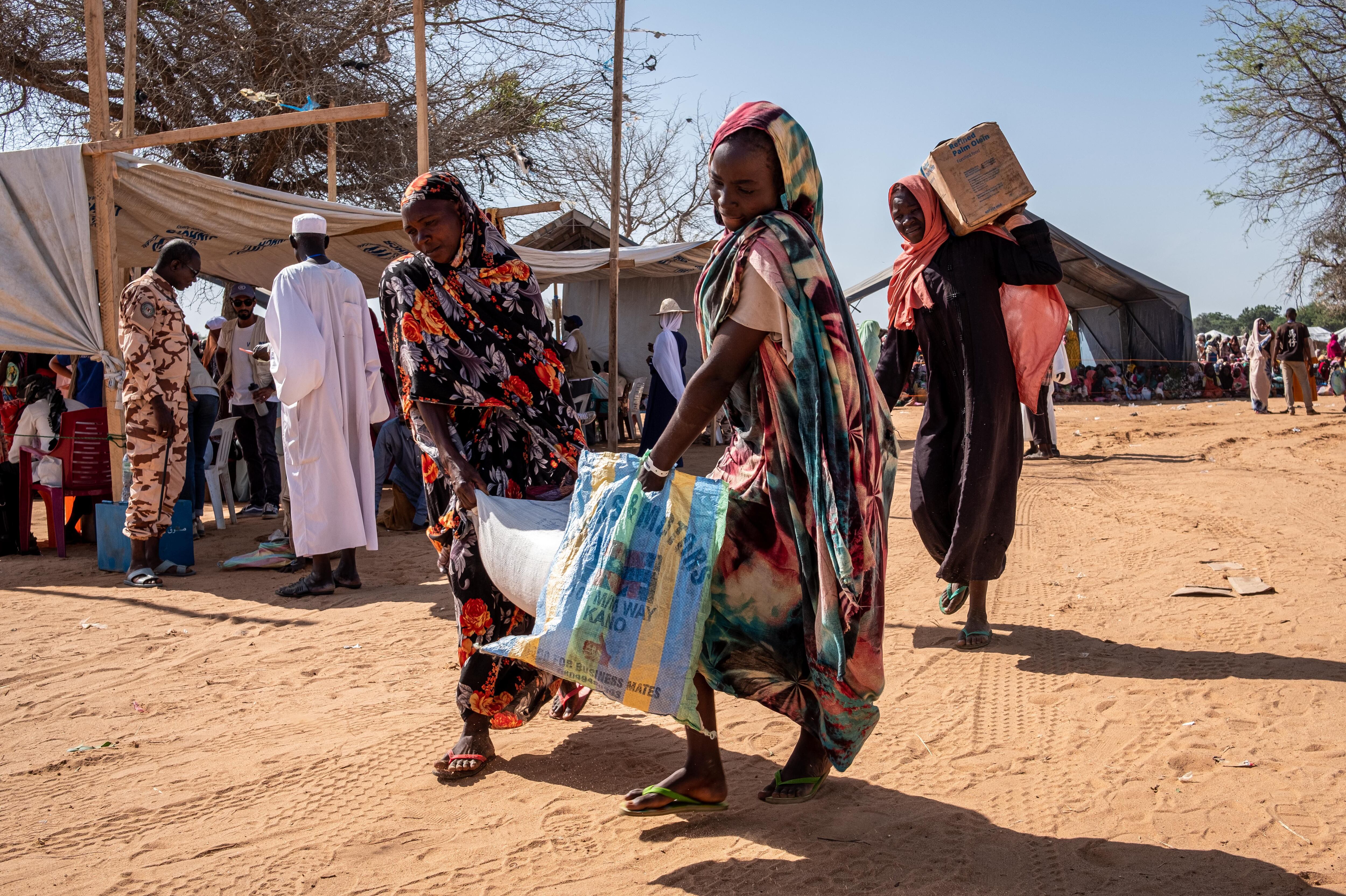 Muchas personas del campo en Chad dependen de la ayuda alimentaria. Soldados chadianos equipados con látigos están listos para intervenir en caso de disturbios en las esperas de la distribución de comida. Las filas revelan la composición del campamento, compuesto principalmente por mujeres y niños, pues para muchos hombres masalit el viaje a Adré es demasiado peligroso.