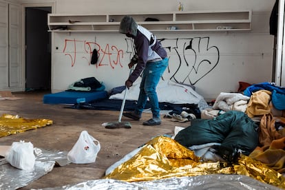 Un residente barre una de las aulas convertidas en dormitorio.
