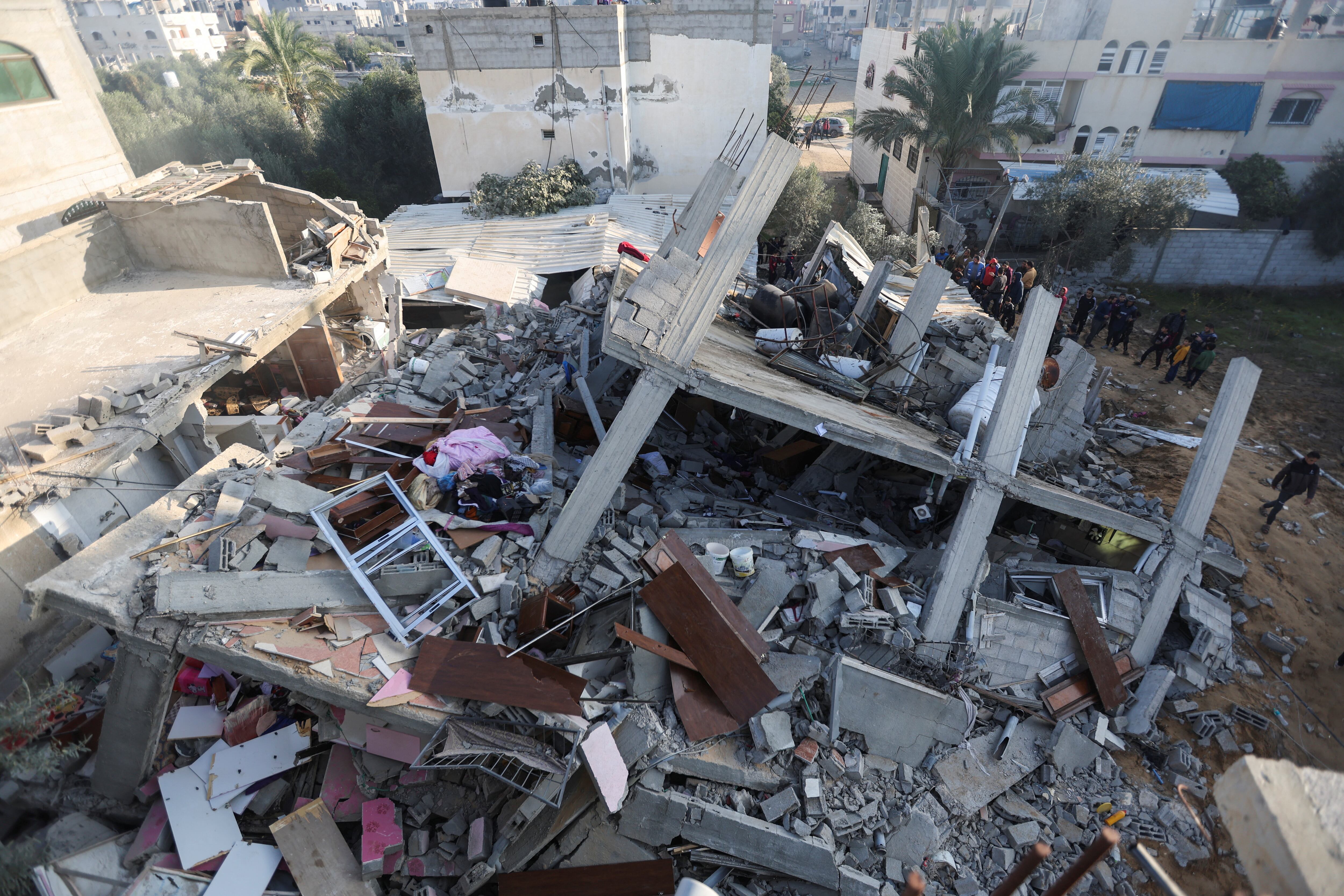 Un grupo de palestinos inspecciona este domingo en Rafah, en el sur de Gaza, los escombros de un edificio derribado por un ataque israelí.