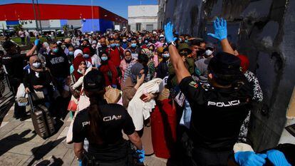 Una pareja de agentes del Cuerpo Nacional de Policía da instrucciones al grupo de 200 marroquíes que hacen  cola para poder pasar a Marruecos a través del paso fronterizo de Beni-Enzar de Melilla.  