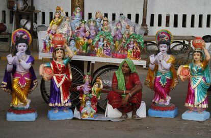 Una vendedora india se sienta en medio de los ídolos hindúes Lord Krishna y su consorte Radha, en la víspera de la festividad de Janmashtami, que celebra el nacimiento de la deidad Krishna.
