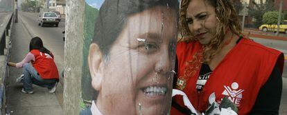 Una mujer retira un cartel electoral del candidato presidencial Alan García el día anterior a las elecciones en junio de 2006 en Perú