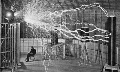 Nikola Tesla, sentado ante uno de sus experimentos.