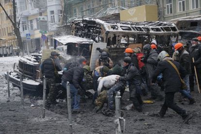 Un grupo de manifestantes trata de ayudar a un compañero herido durante los enfrentamientos con la policía, en Kiev