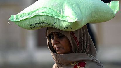 Una mujer lleva un saco de harina de trigo en Islamabad (Pakistán).
