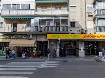 Varias personas con mascarilla hacen cola en un supermercado Ahorra Más a primera hora de la mañana, en Alcorcón.