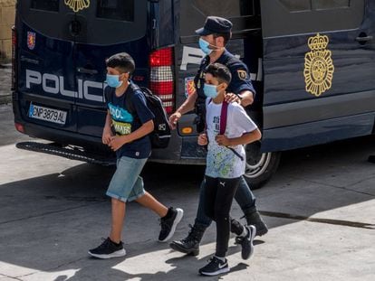 Un policía nacional acompaña a dos menores, el pasado 20 de mayo, en Ceuta.