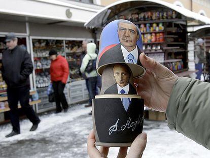 Un vendedor muestra una tradicional <i>matrioshka</i> rusa con los retratos de Dmitri Medvédev y Vladímir Putin en San Petersburgo.