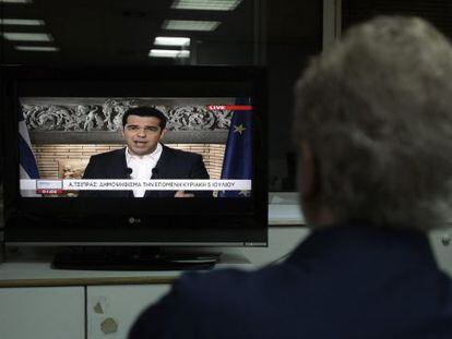 Un home veu el missatge televisat de Tsipras. 