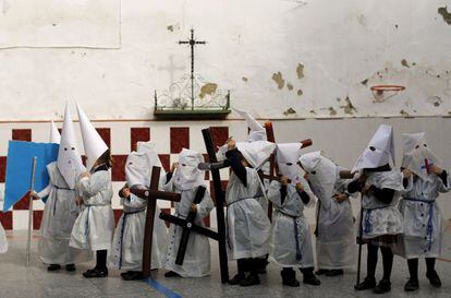 Un grupo de niños vestidos de nazarenos se colocan las capuchas después de participar en una procesión en una escuela de Sevilla.