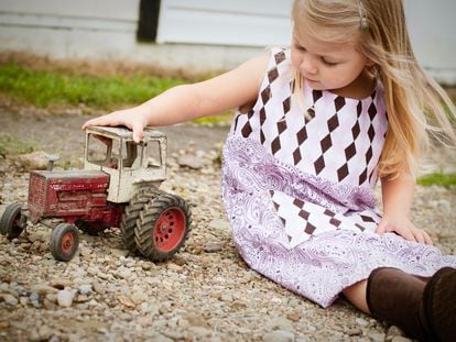 Una niña juega con un tractor viejo.