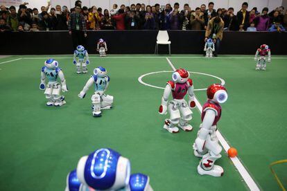 Varias personas observan un partido de fútbol entre robots NAO en las instalaciones de la Conferencia Mundial de Robots en Pekín.