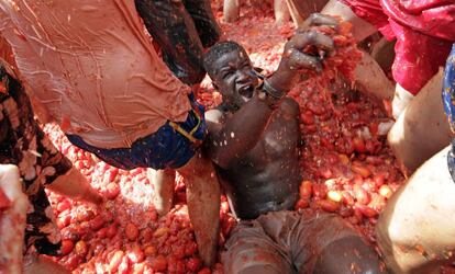 Un participante en la fiesta de La Tomatina en el suelo durante la guerra de tomates en Buñol (Comunidad Valenciana).