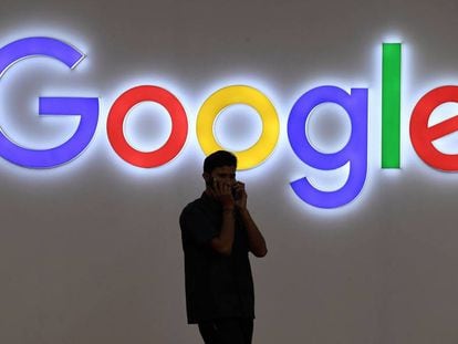Un hombre habla por tel&eacute;fono frente a un cartel de Google