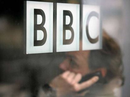 Un hombre habla por teléfono tras un cristal con el logo de la BBC