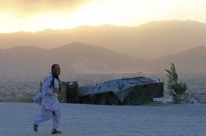 Un afgano corre junto a los restos de un tanque en Kabul, en la tarde del jueves.