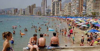 Veraneantes con alojamientos turísticos de fondo en Benidorm.