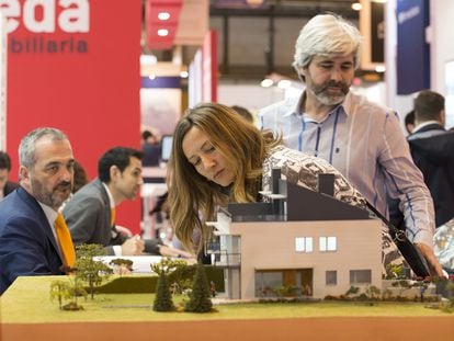 Visitantes del SIMA de Madrid miran una maqueta de una promoción de viviendas.