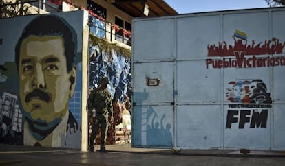 Un soldado venezolano, el pasado lunes, junto a un mural dedicado a Nicolás Maduro en la entrada de un colegio de Caracas.