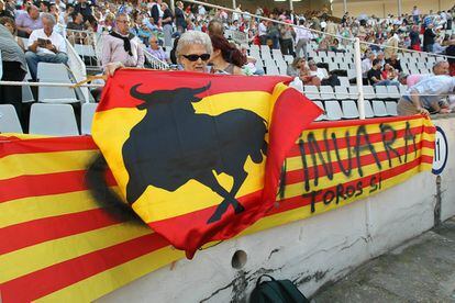 Una aficionada posa con una bandera de España con un gran toro, mientras que la plaza se adorna con una 'senyera' con el emblema de 'toros sí'.