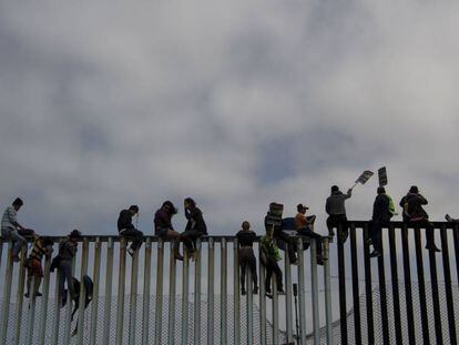 La gente se sienta en la valla fronteriza en Tijuana, en abril.