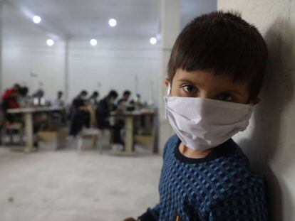 Un niño observa cómo un grupo de voluntarios hacen máscaras faciales protectoras en un taller en la ciudad de Idlib, en el noreste de Siria.  