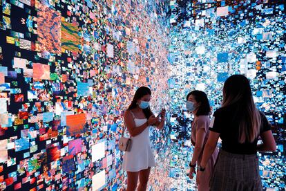 Tres visitantes a la Feria de Arte Digital de Hong Kong junto a una obra inmersiva de Refik Anadol que se convertirá en un certificado digital único (NFT) y se subastará en Sotheby's.