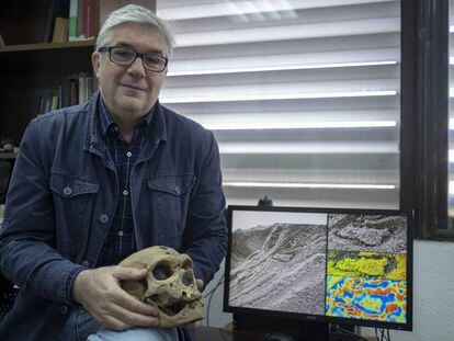 Fernando Muñiz, uno de los investigadores de las huellas de los neandertales, sostiene la reproducción de un cráneo de estos homínidos mientras muestra la huella hallada en Gibraltar.
 