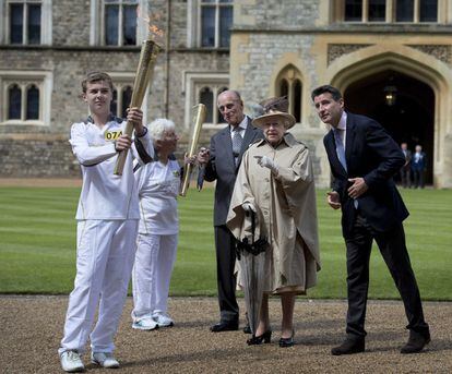 La reina Isabel II de Inglaterra y el príncipe Felipe de Edimburgo, junto al medallista olímpico Sebastian Coe y la portadora de la antorcha olímpica, Gina McGregor, observan a Phil Wells portar la antorcha olímpica en el castillo de Windsor el 10 de julio de 2012. 