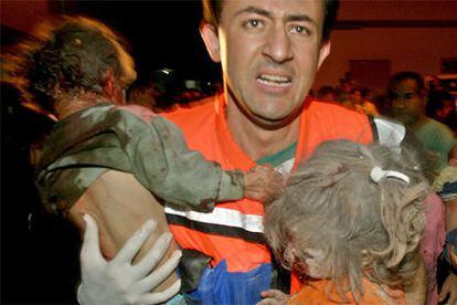 Un médico palestino evacúa a dos menores heridos.