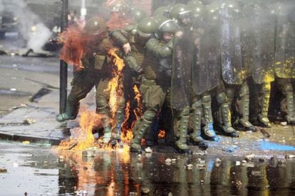 El fuego de un c&oacute;ctel molotov alcanza a dos polic&iacute;as durante las manifestaciones del domingo en Santiago de Chile.